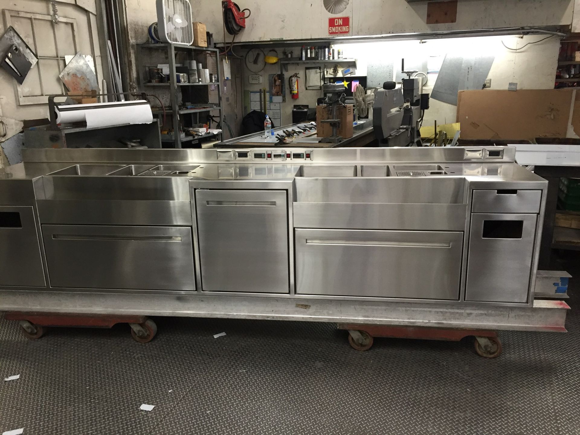 Stainless steel commercial kitchen island on a wheeled platform, indoors.