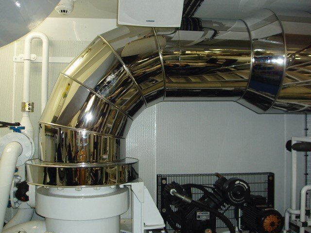 Shiny metallic pipe bends, part of a system in an interior mechanical room.
