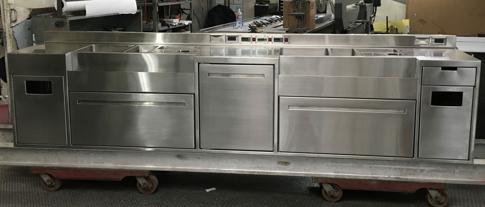 Stainless steel commercial kitchen counter on a wheeled platform.