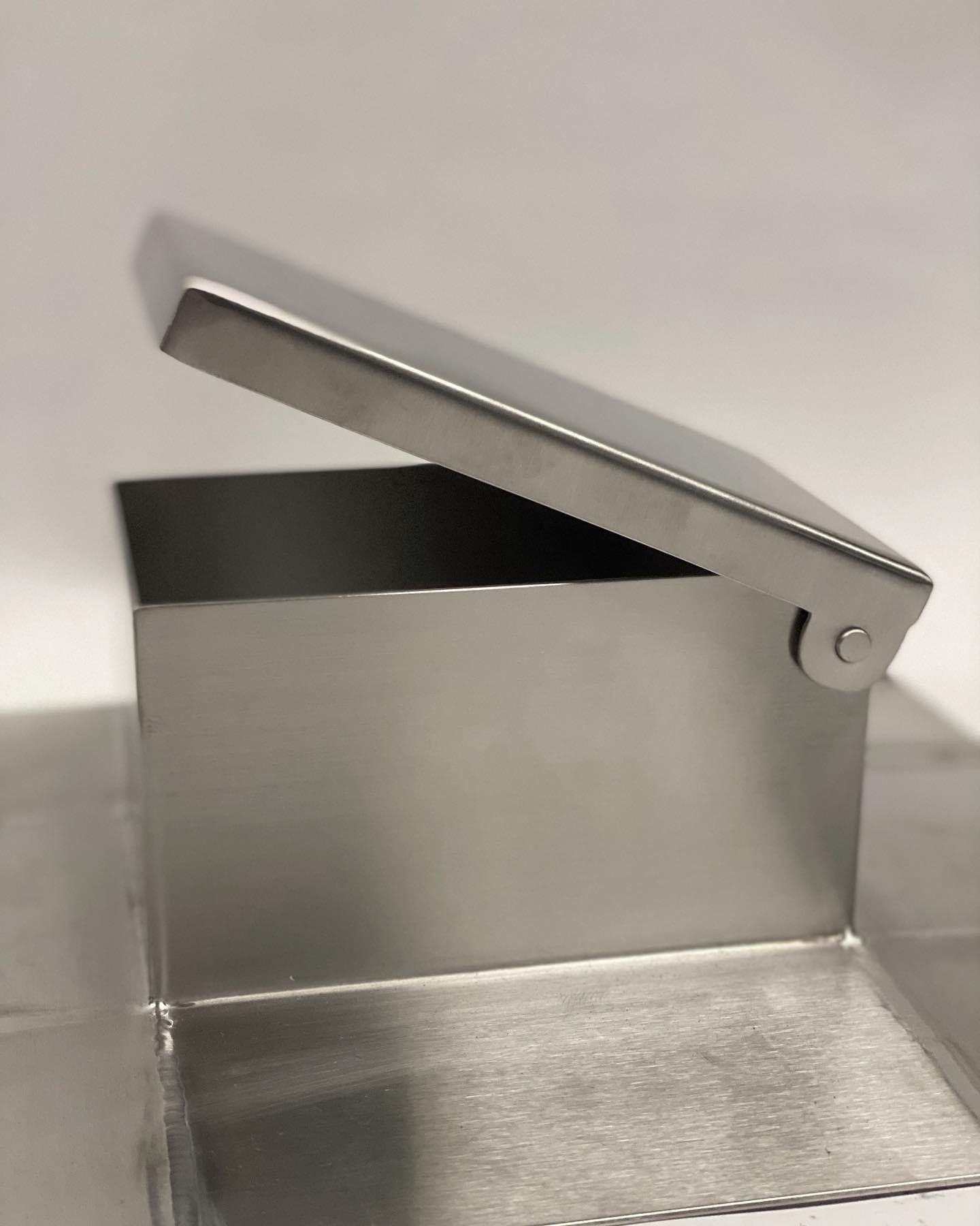 A small, open metal box with a hinged lid.