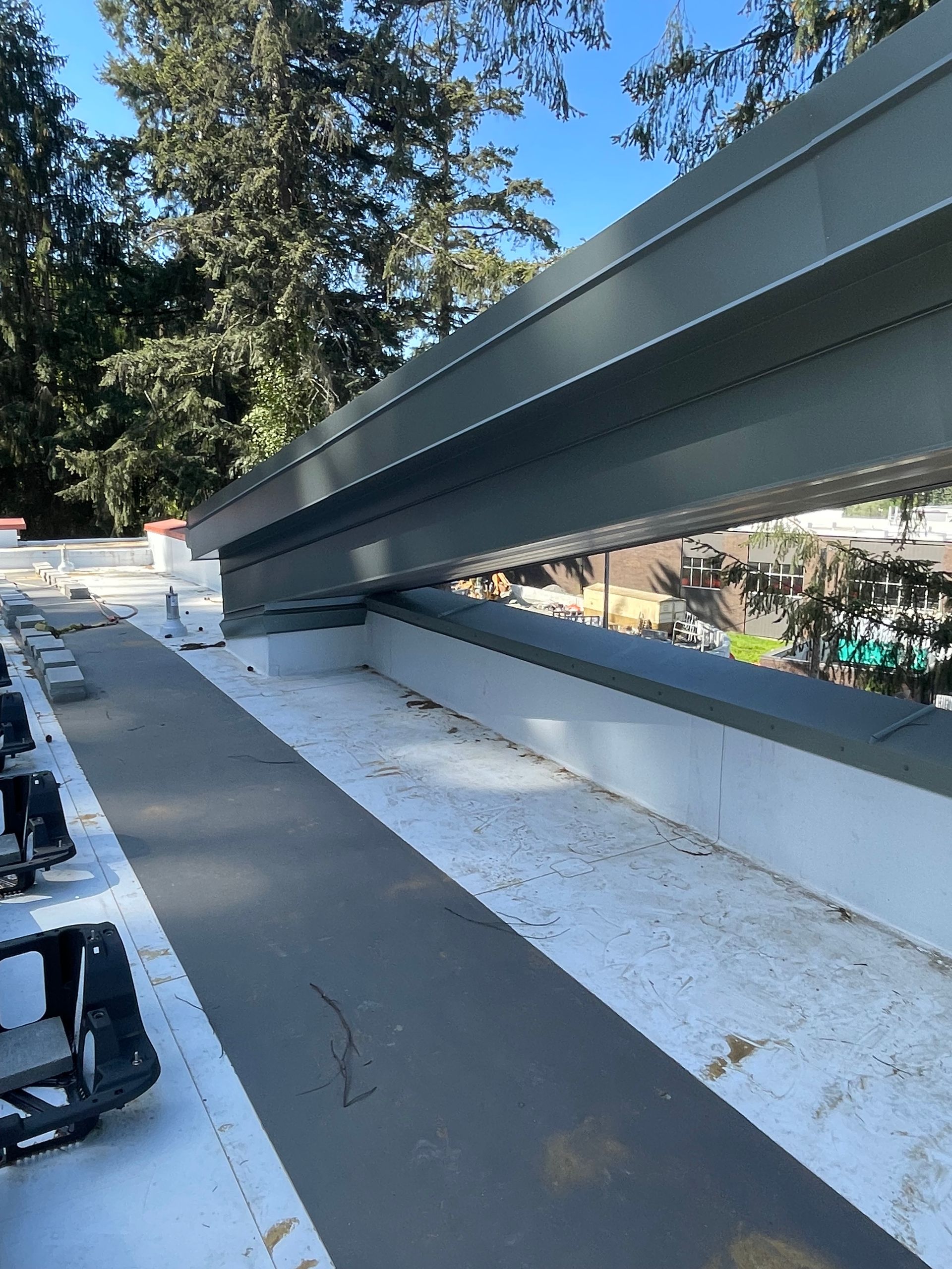 A rooftop with large steel beams extending over a white and dark gray surface.