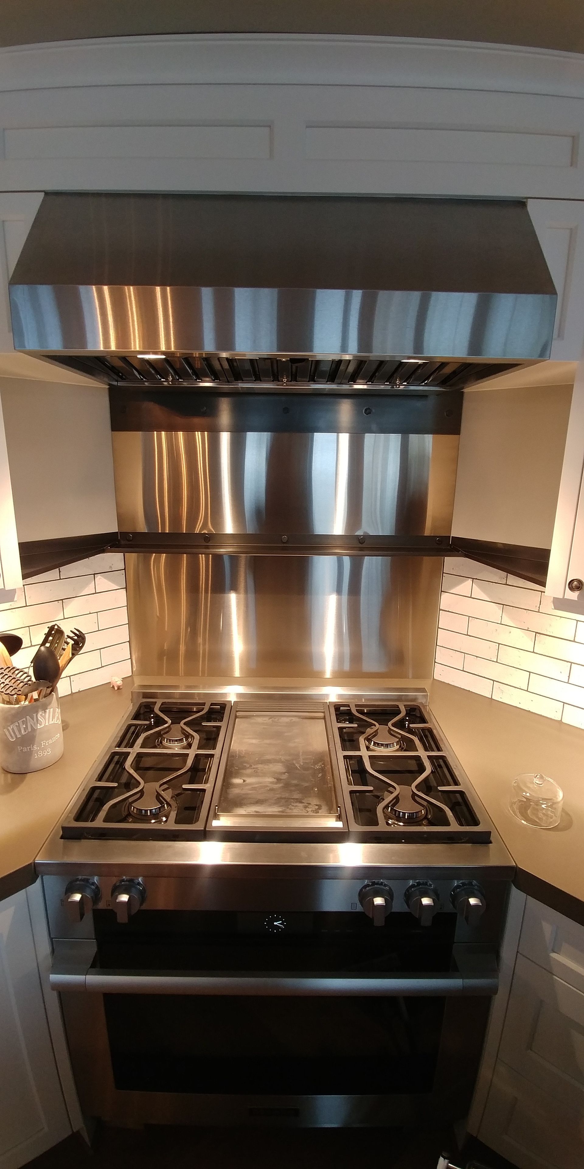 Stainless steel stove and range hood in a kitchen setting.