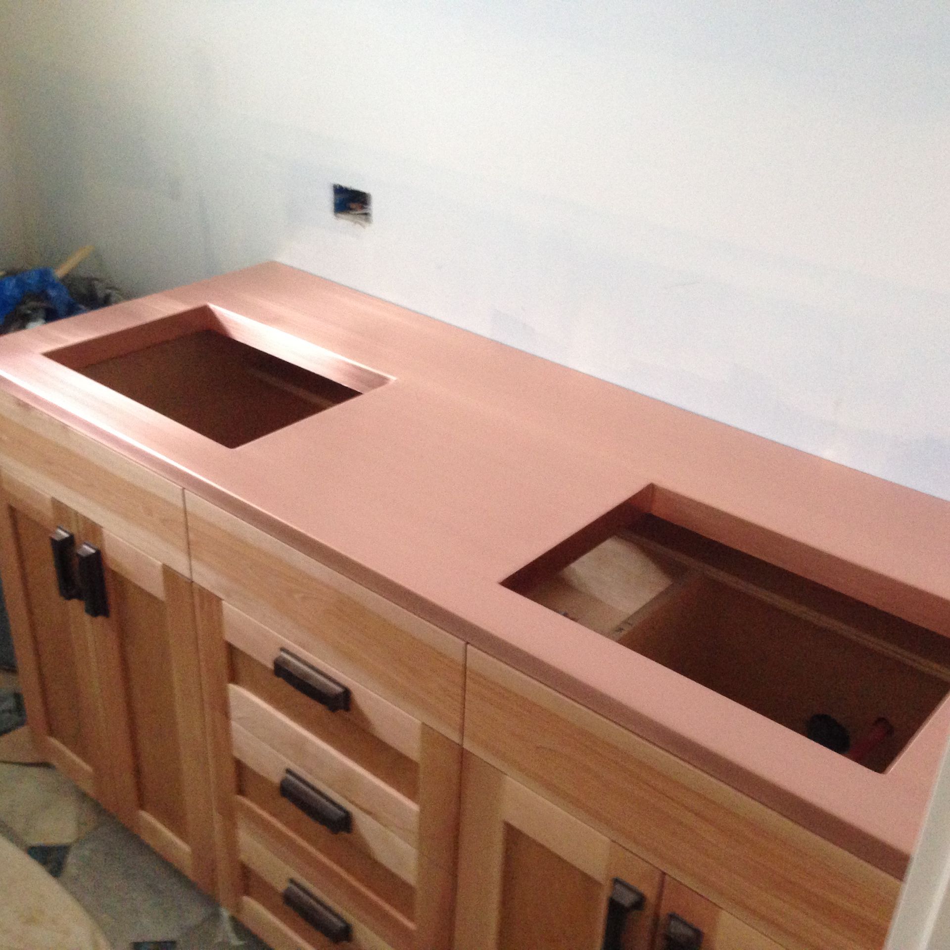 Copper countertop with two sink cutouts on a wooden vanity.