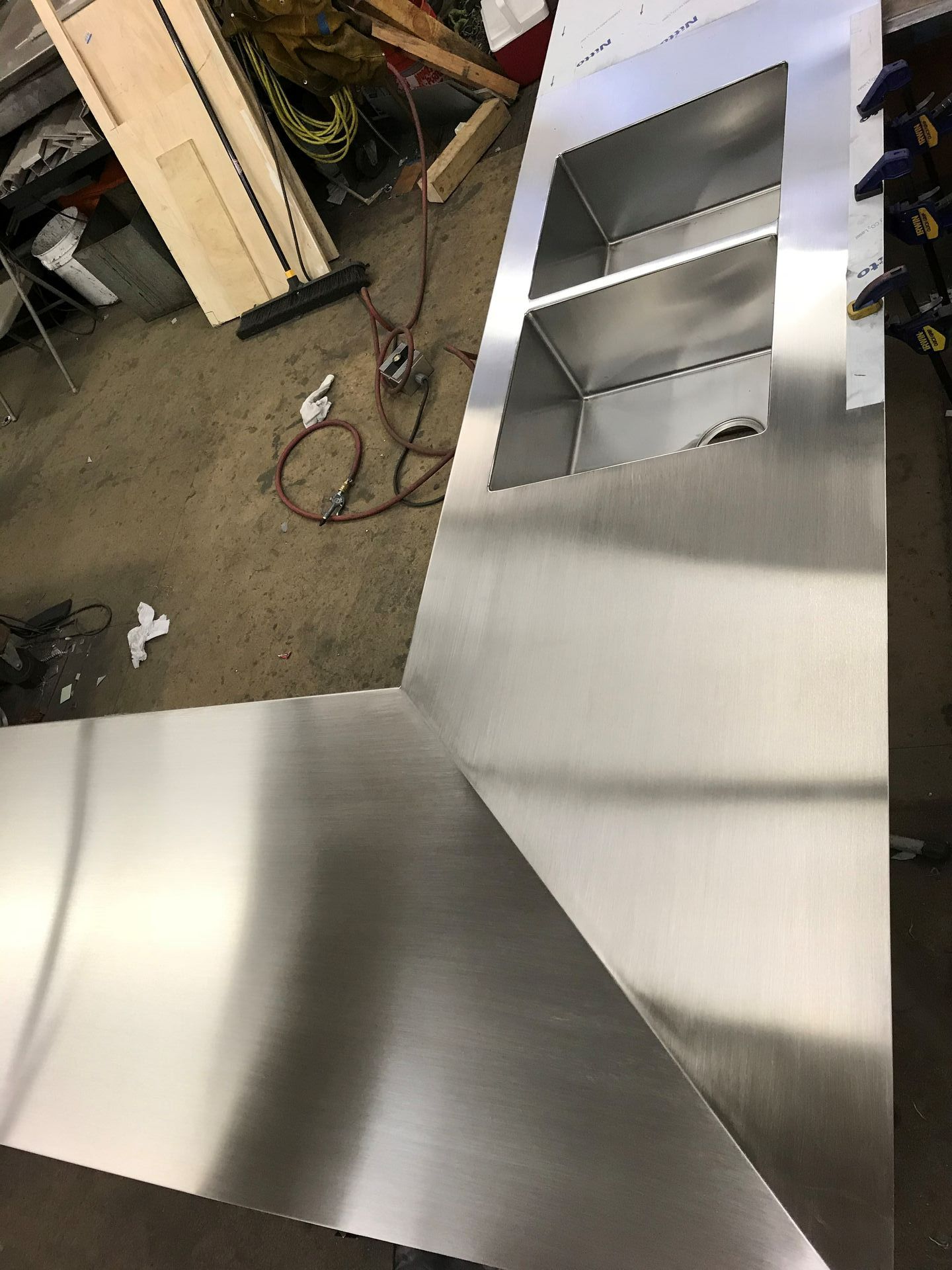 Stainless steel kitchen hood with interior shelves under construction in a workshop.