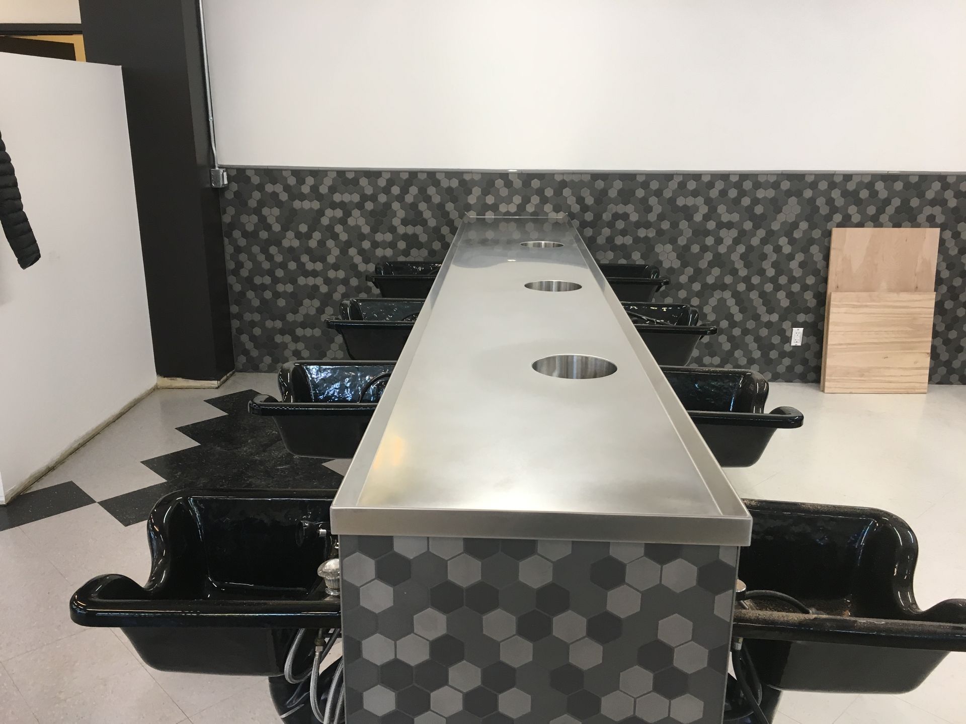 Hair salon wash stations with stainless steel countertop and honeycomb tile base.