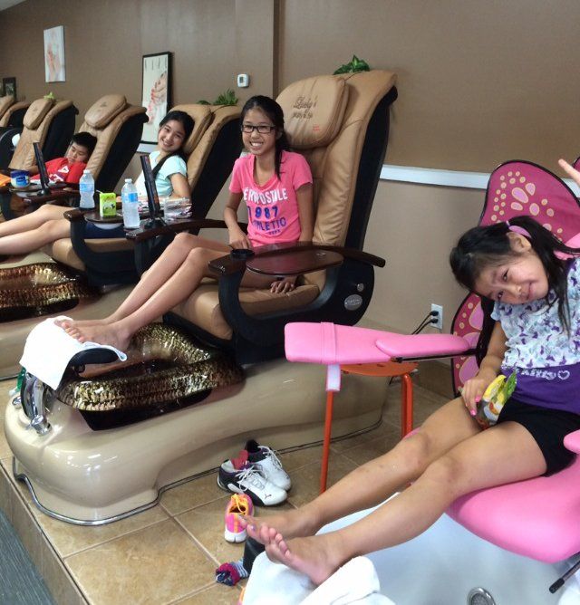 Children getting pedicures in a nail salon. Girls sitting in spa chairs with feet in water.