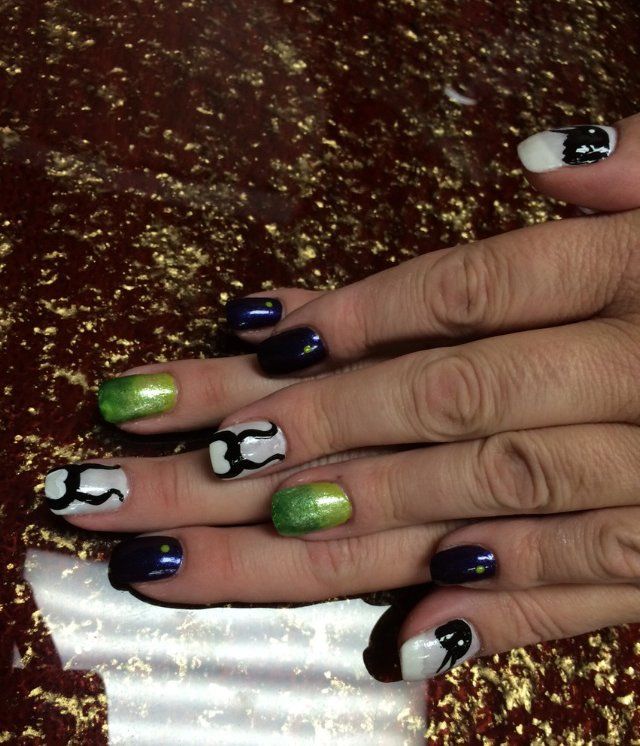 Hands with colorful nail art: white, black, green, and purple designs on a gold glitter background.