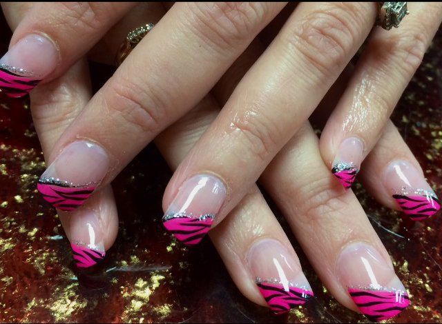 Close-up of hands with pink and black zebra-striped French tip nails.