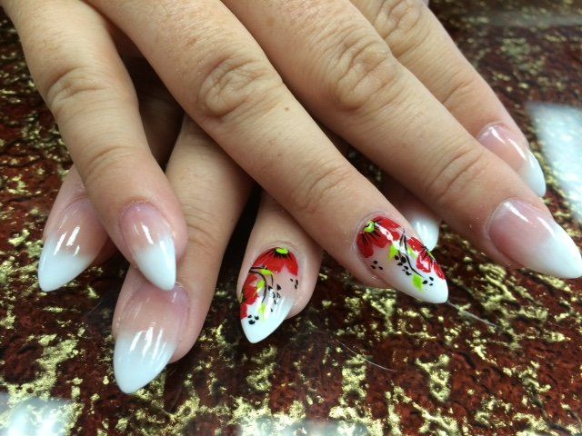 Hands with stiletto-shaped nails; French tip gradient, one decorated with red floral art.