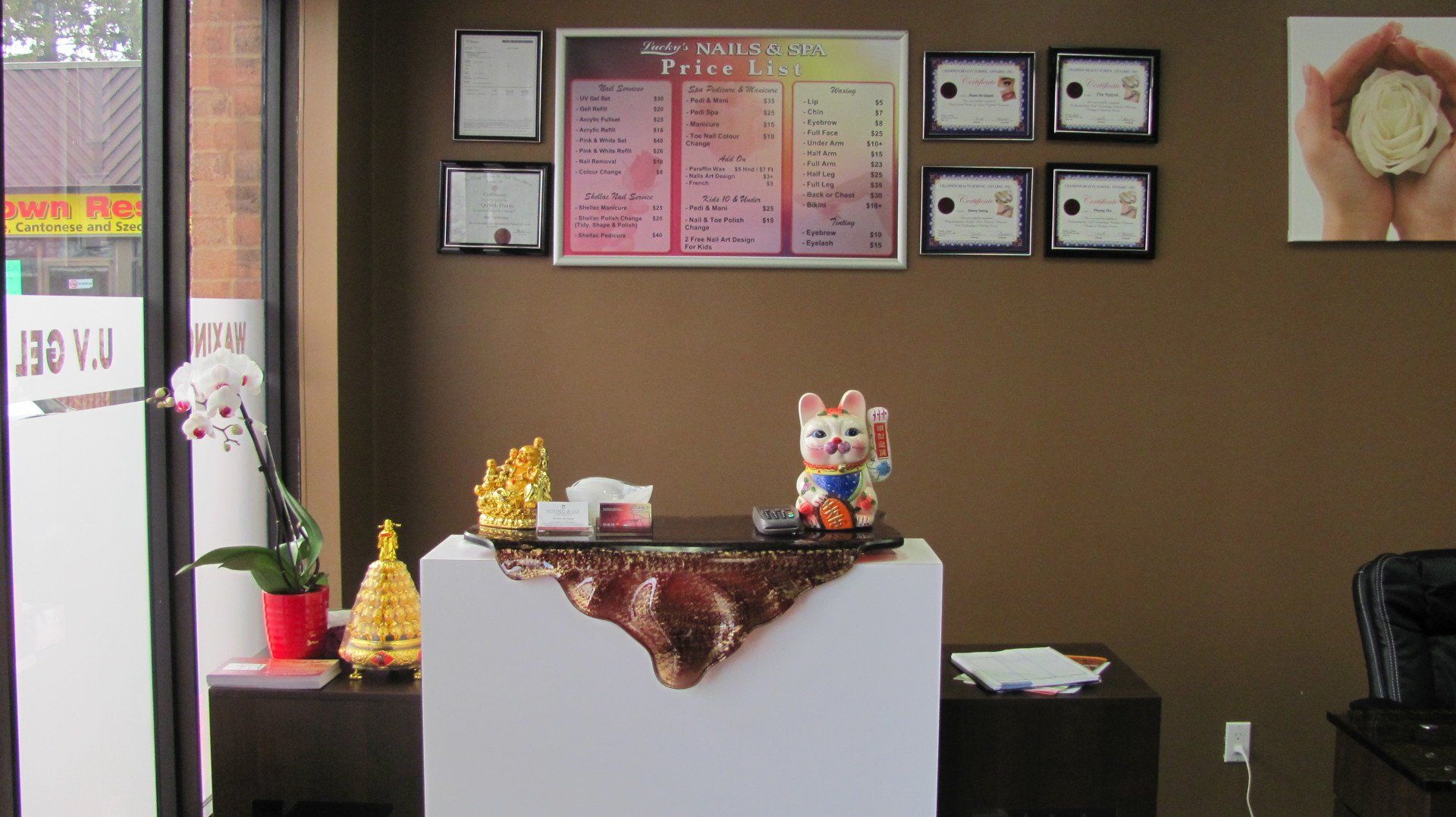 Interior view of a business: reception desk with decorations, menu, and framed certificates on brown wall.