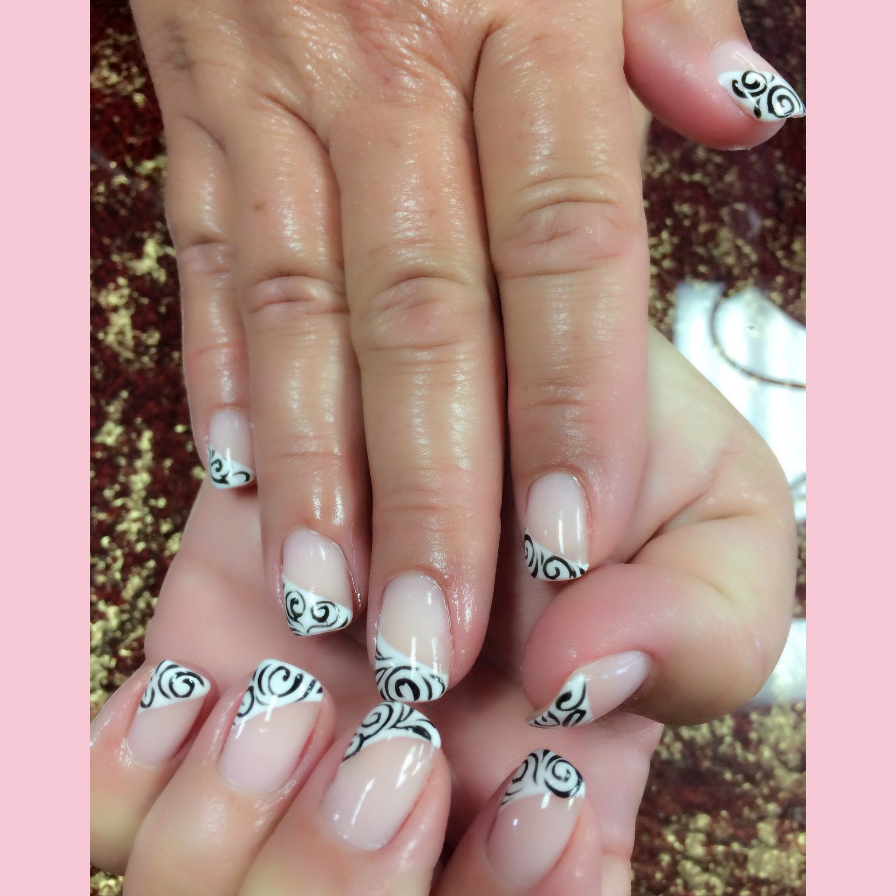 Manicured nails with clear polish and black scrollwork design.