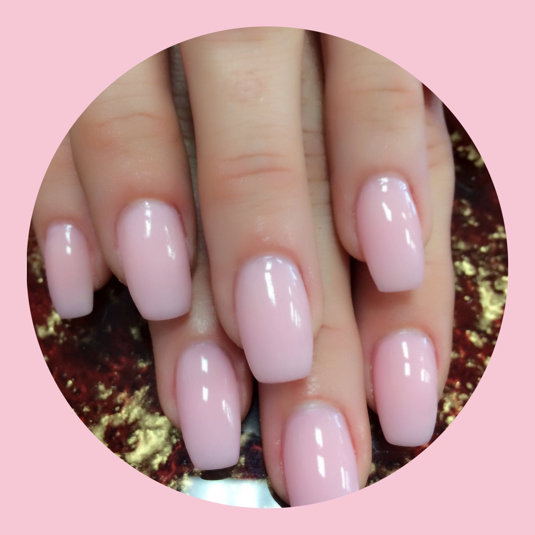 Close-up of a hand with neatly manicured nails painted a light pink color.
