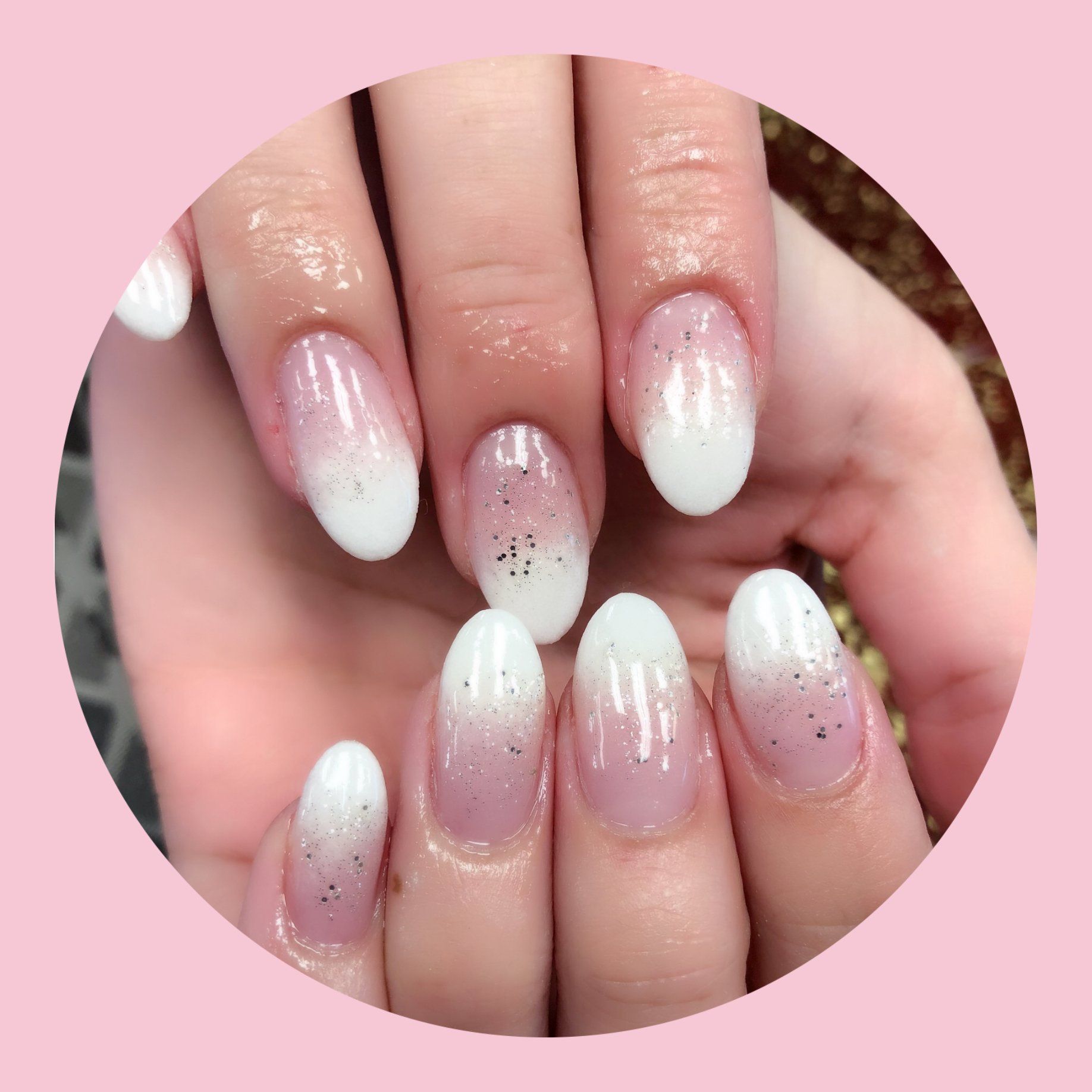 Oval-shaped nails with a white to pink ombre effect, sparkling glitter.