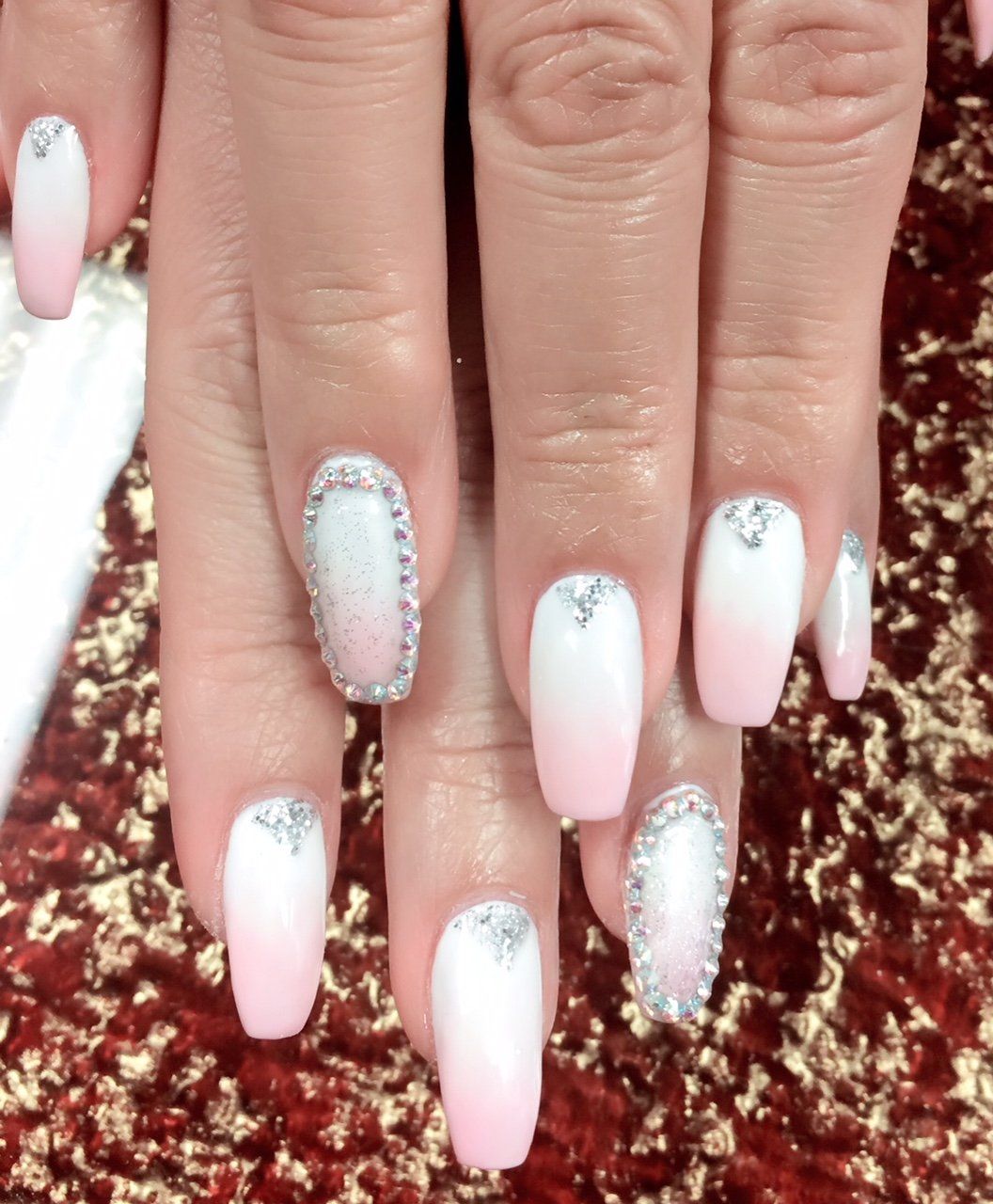 Light pink and white ombre nails with silver glitter accents on a hand.