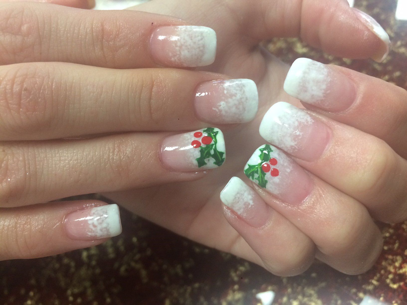 Christmas-themed nail art featuring French tips with a frosted effect and holly berry designs.