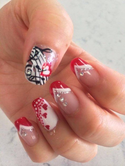 Hand with red and white nail art, including abstract designs and embellishments.