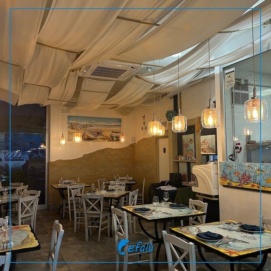 Un ristorante con tavoli e sedie e un cartello che dice Cefalù