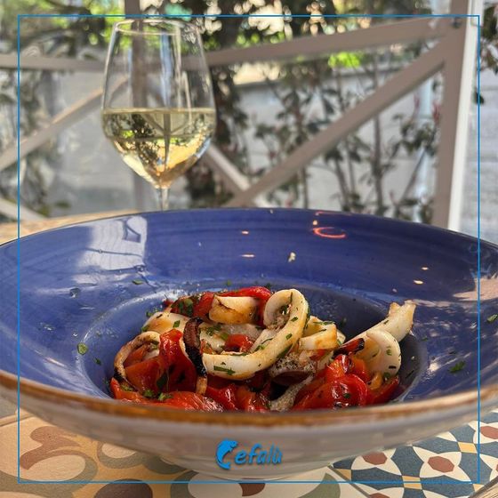 Una ciotola di cibo con un bicchiere di vino sullo sfondo
