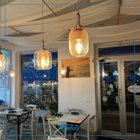 Un ristorante con tavoli, sedie e luci appese al soffitto.