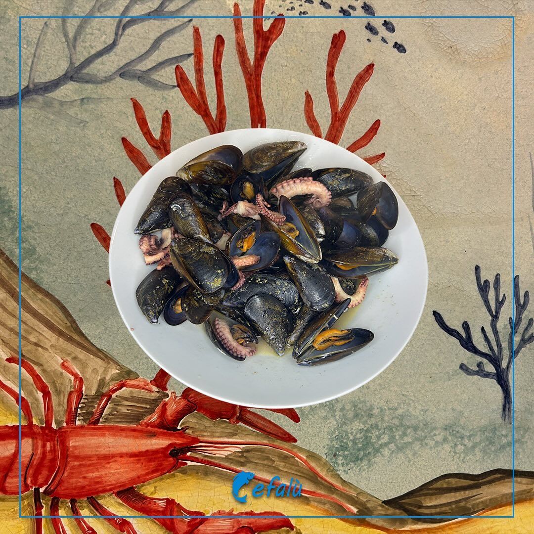 Un piatto di cozze con un'aragosta sullo sfondo