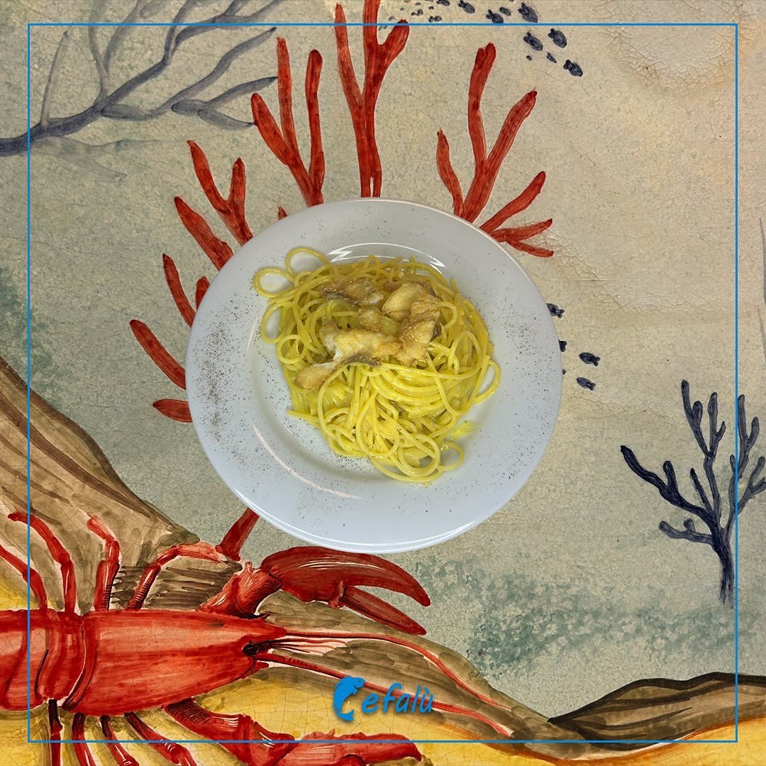 Un piatto di spaghetti con un'aragosta sullo sfondo