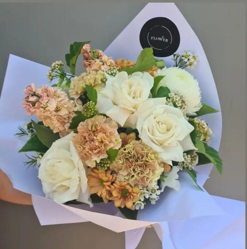 a person is holding a bouquet of flowers wrapped in white paper
