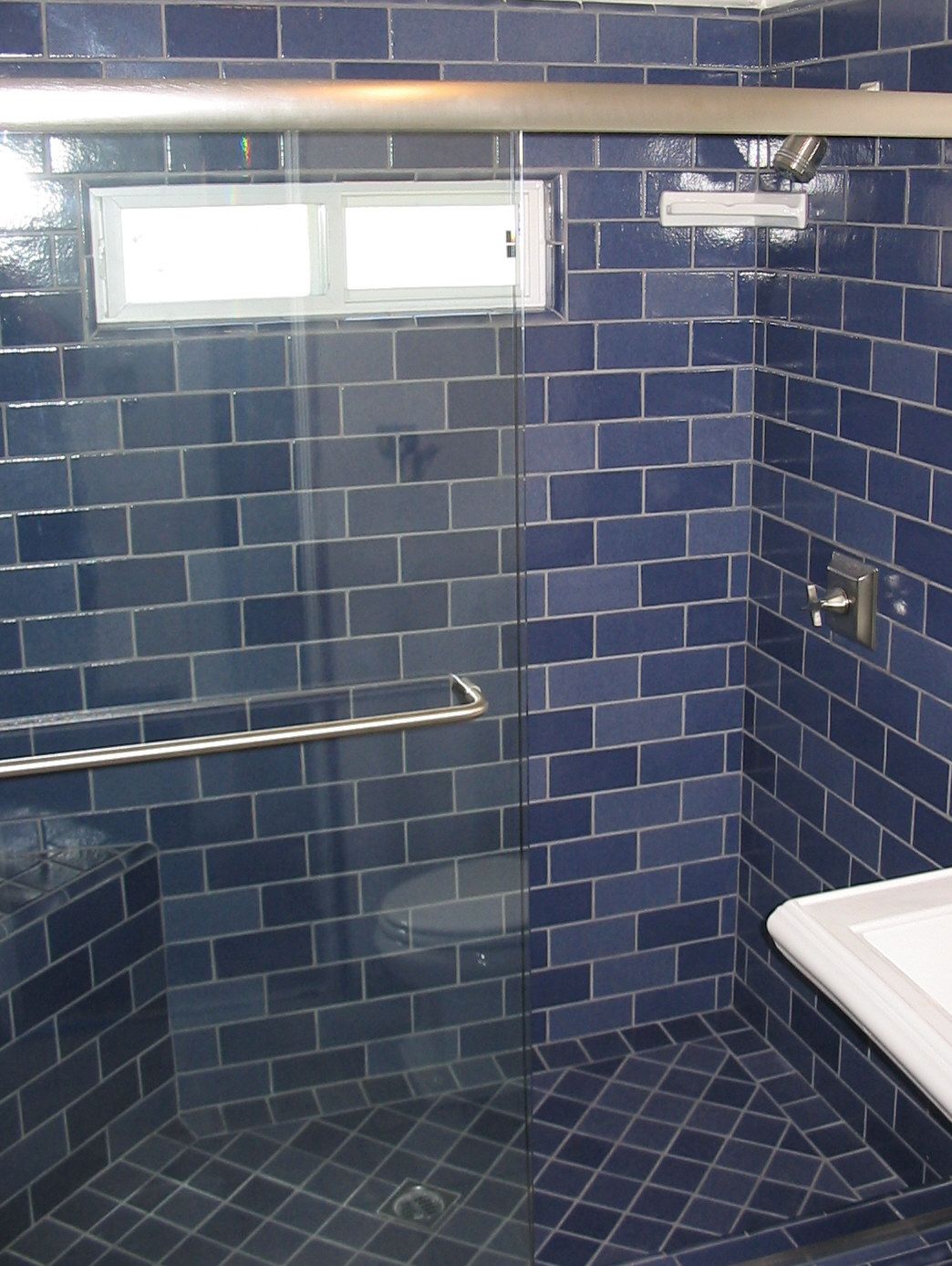 A Bathroom With Blue Tiles And A Sliding Glass Door -  Los Angeles, CA - New Castle Remodeling