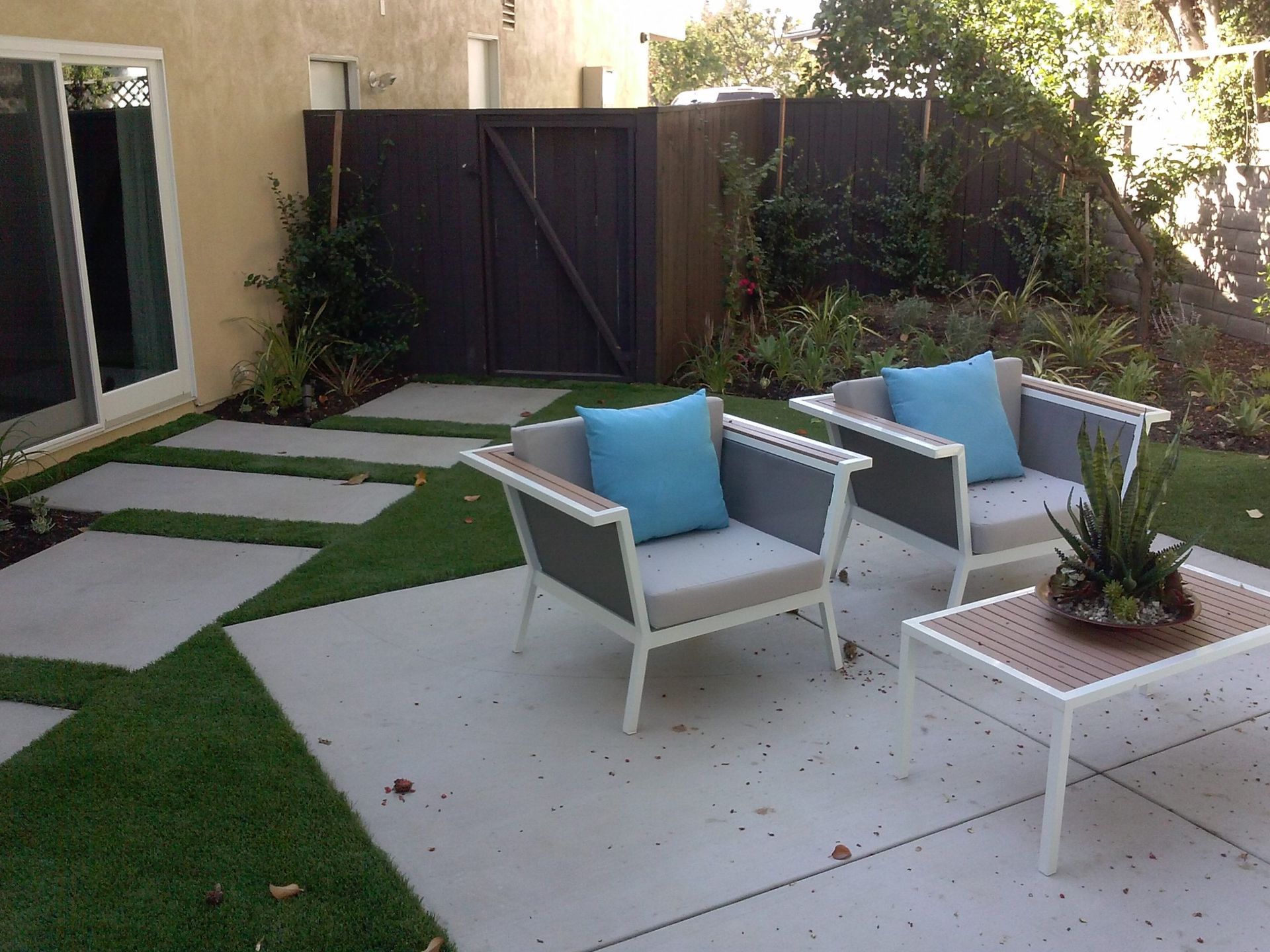 A Patio With Two Chairs And A Table With Blue Pillows -  Los Angeles, CA - New Castle Remodeling
