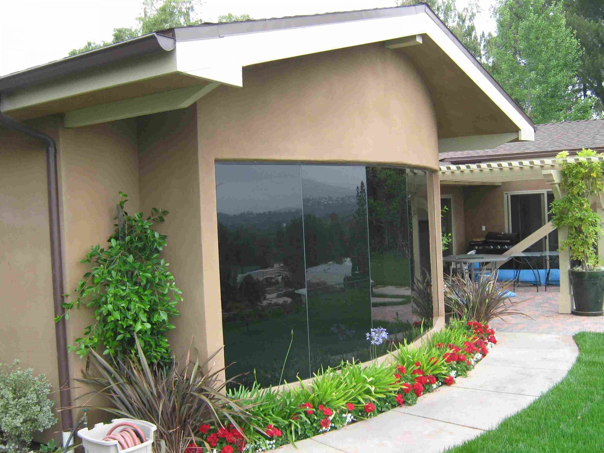 A House With A Large Window Surrounded By Flowers -  Los Angeles, CA - New Castle Remodeling