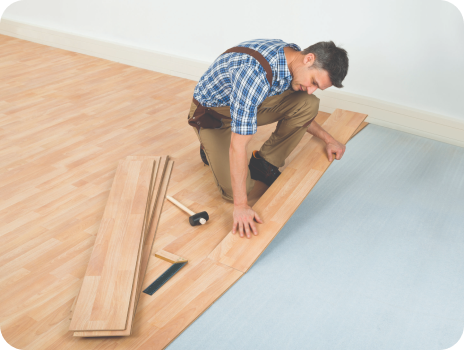 A man is installing a wooden floor in a room.
