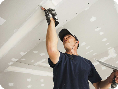A man is plastering a ceiling with a spatula.