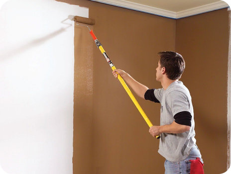 A man is painting a wall with a paint roller
