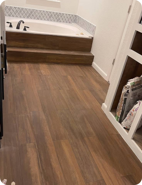 A bathroom with a bathtub and wooden floors.
