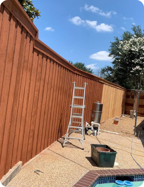 A wooden fence is being painted next to a pool.