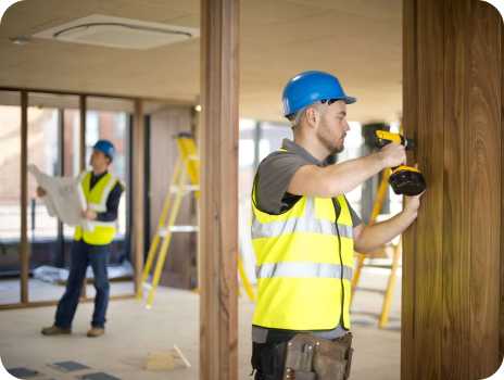 Two construction workers are working on a wooden wall.