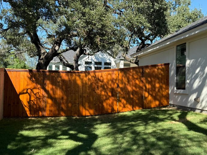 A wooden fence is in the backyard of a house.