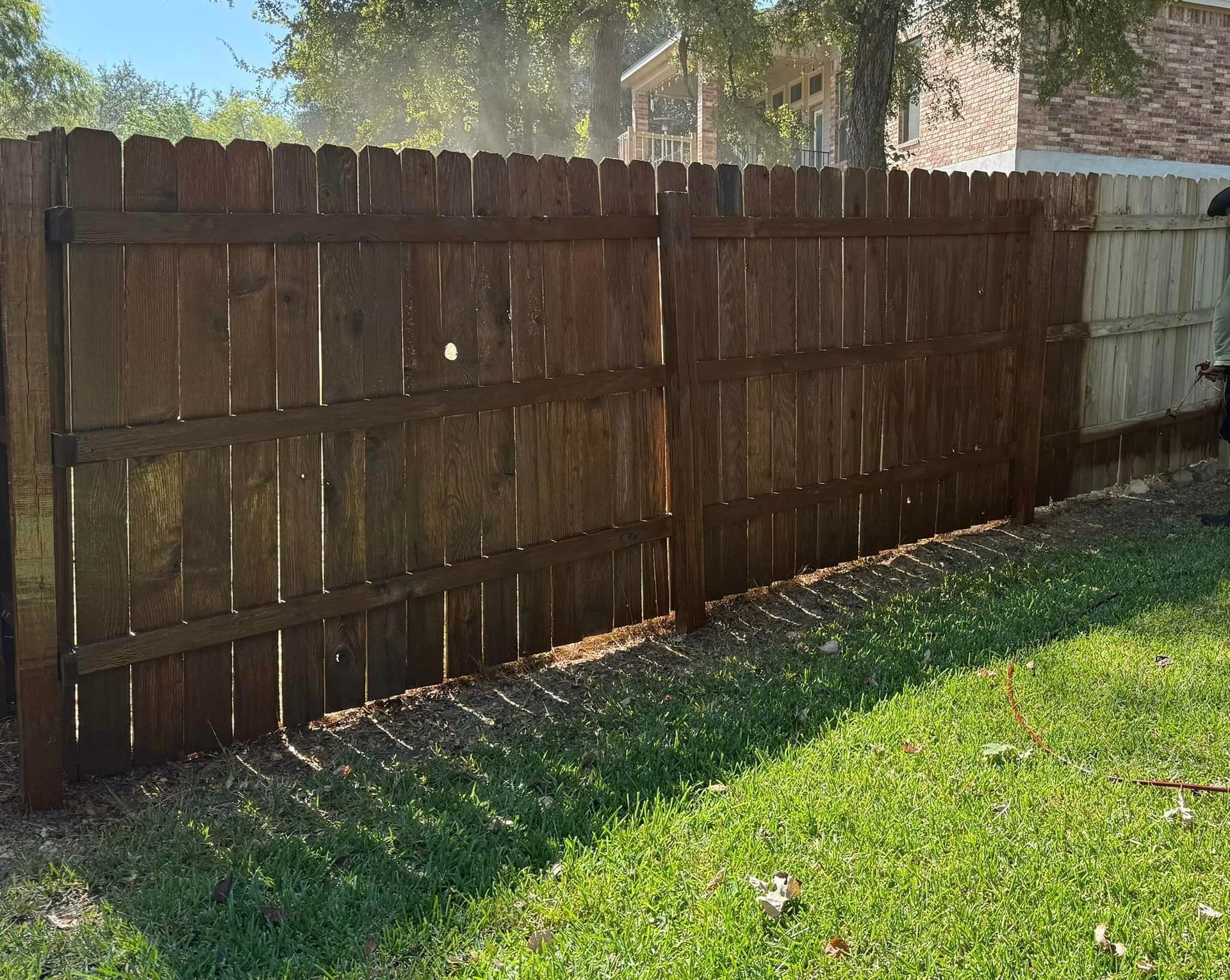 A wooden fence is sitting in the middle of a lush green yard.