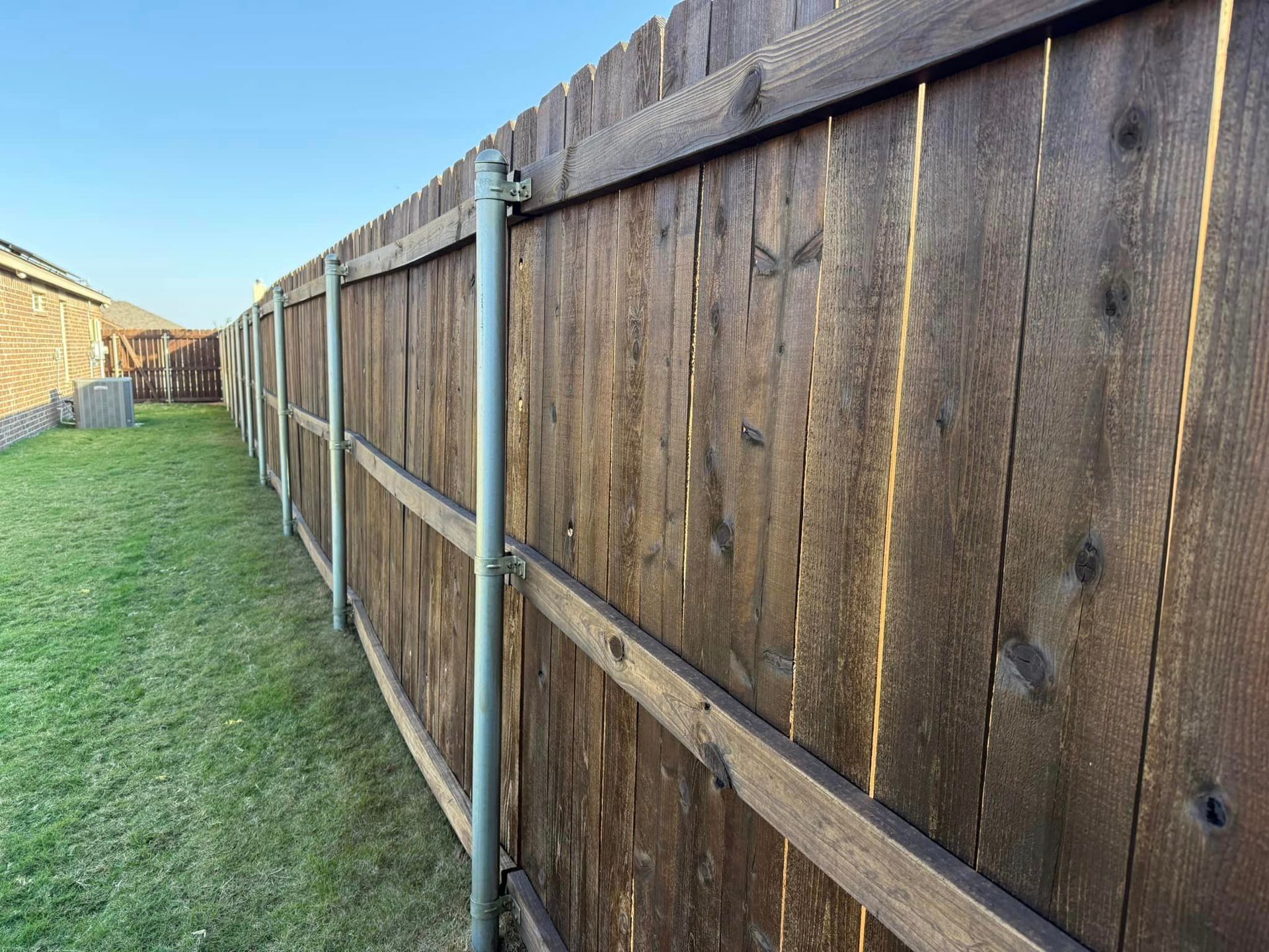 A wooden fence surrounds a lush green yard.