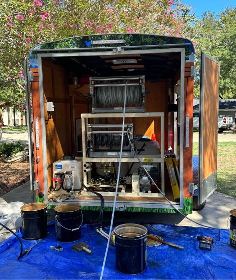 A trailer with a machine inside of it is sitting on a blue tarp.