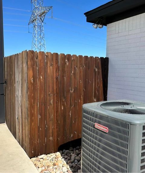 A wooden fence behind a carrier air conditioner