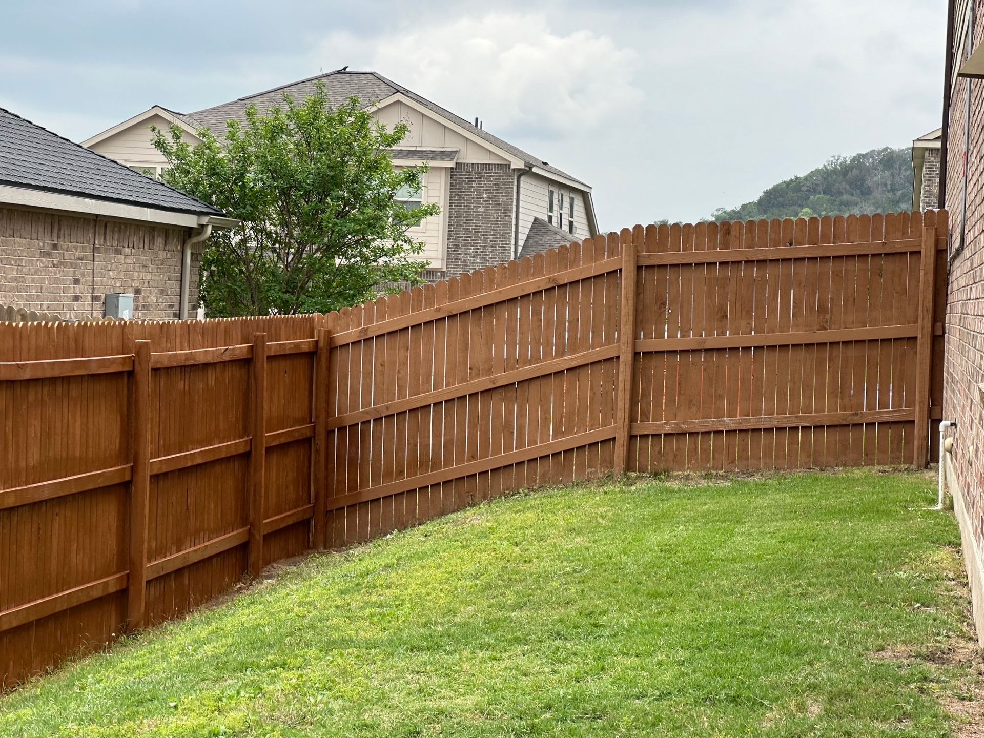 A wooden fence is surrounded by trees in a yard.