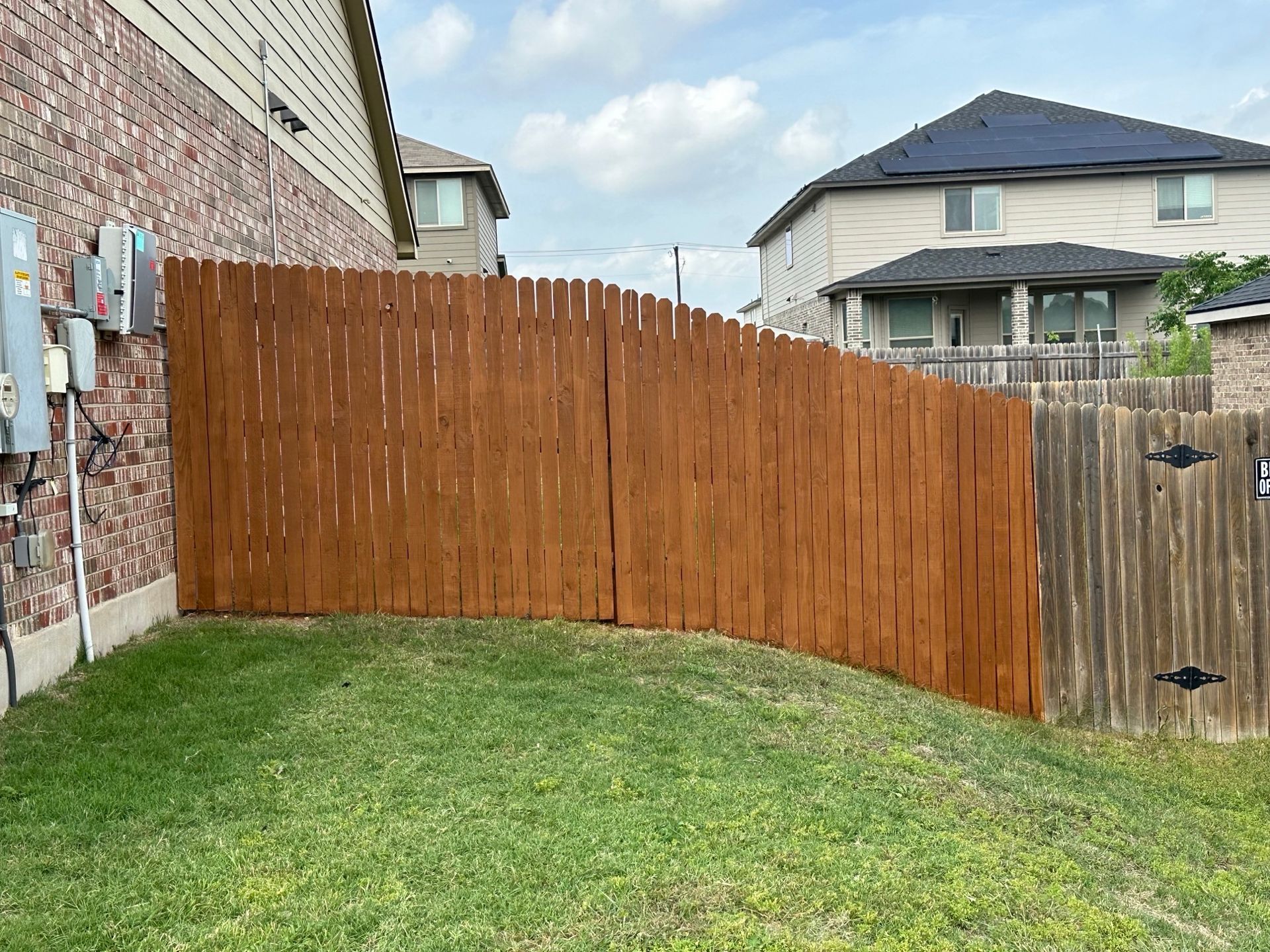 A wooden fence is in the backyard of a house.