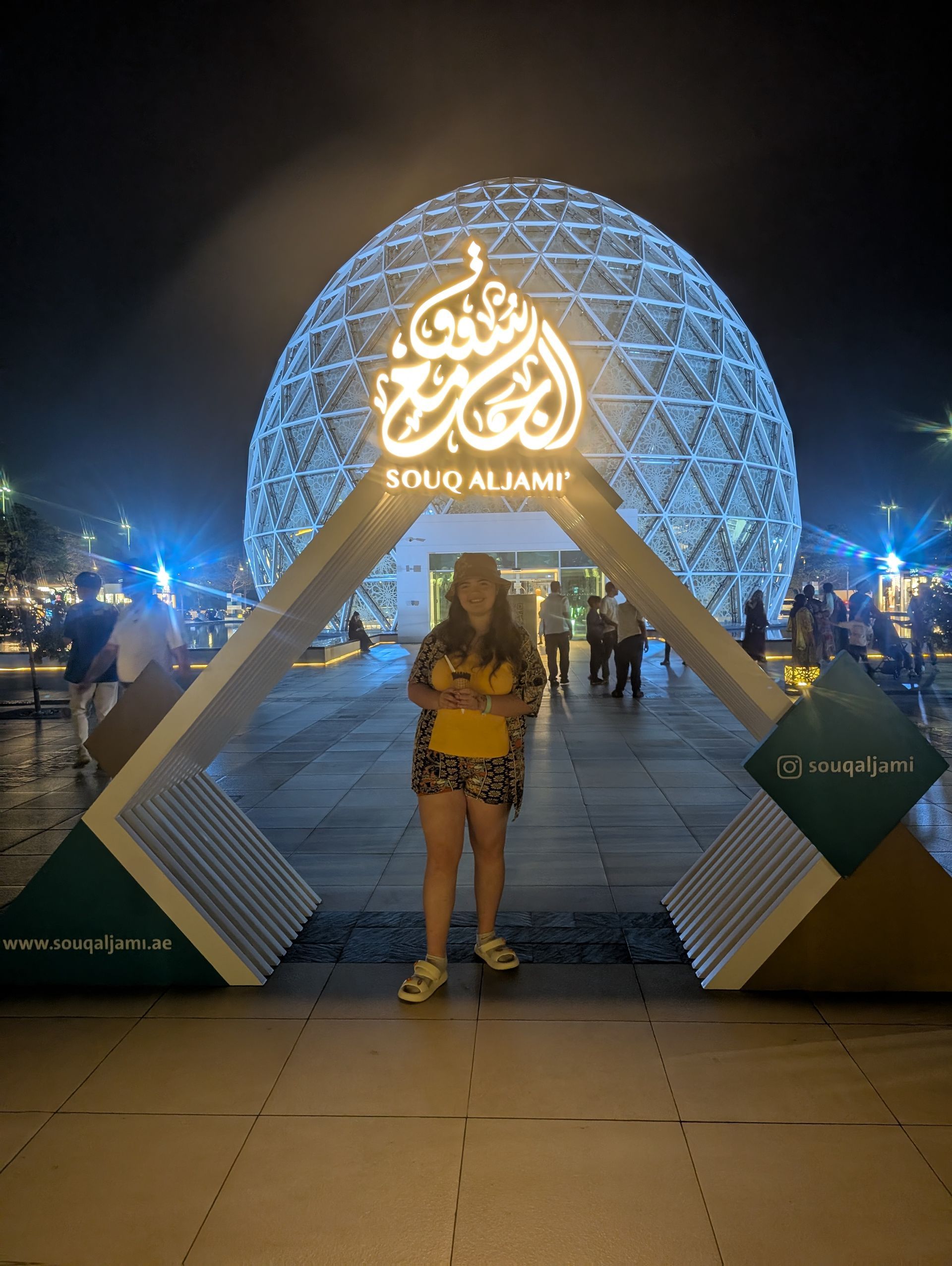 Woman stands beneath an illuminated archway, 