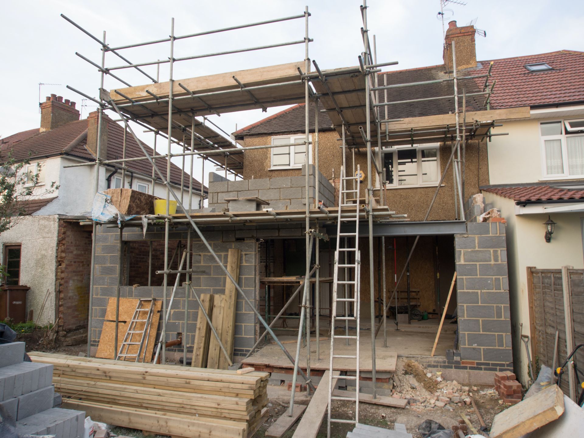 a house under construction with scaffolding and a ladder