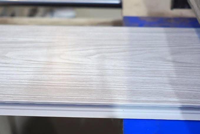 Primer plano de una superficie de metal cepillado con una base azul en un entorno industrial.