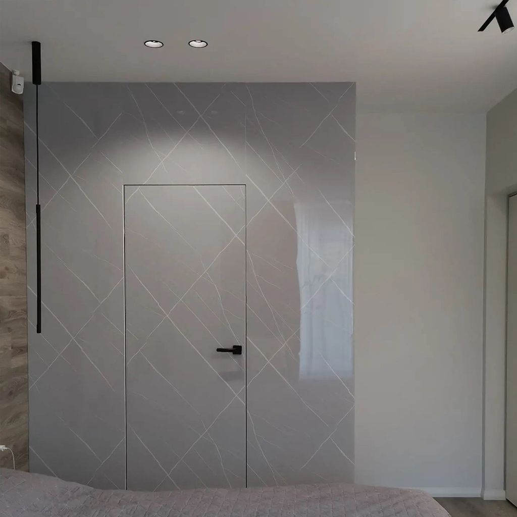 Interior moderno con una pared decorativa de mármol gris y una puerta lisa con tirador negro.