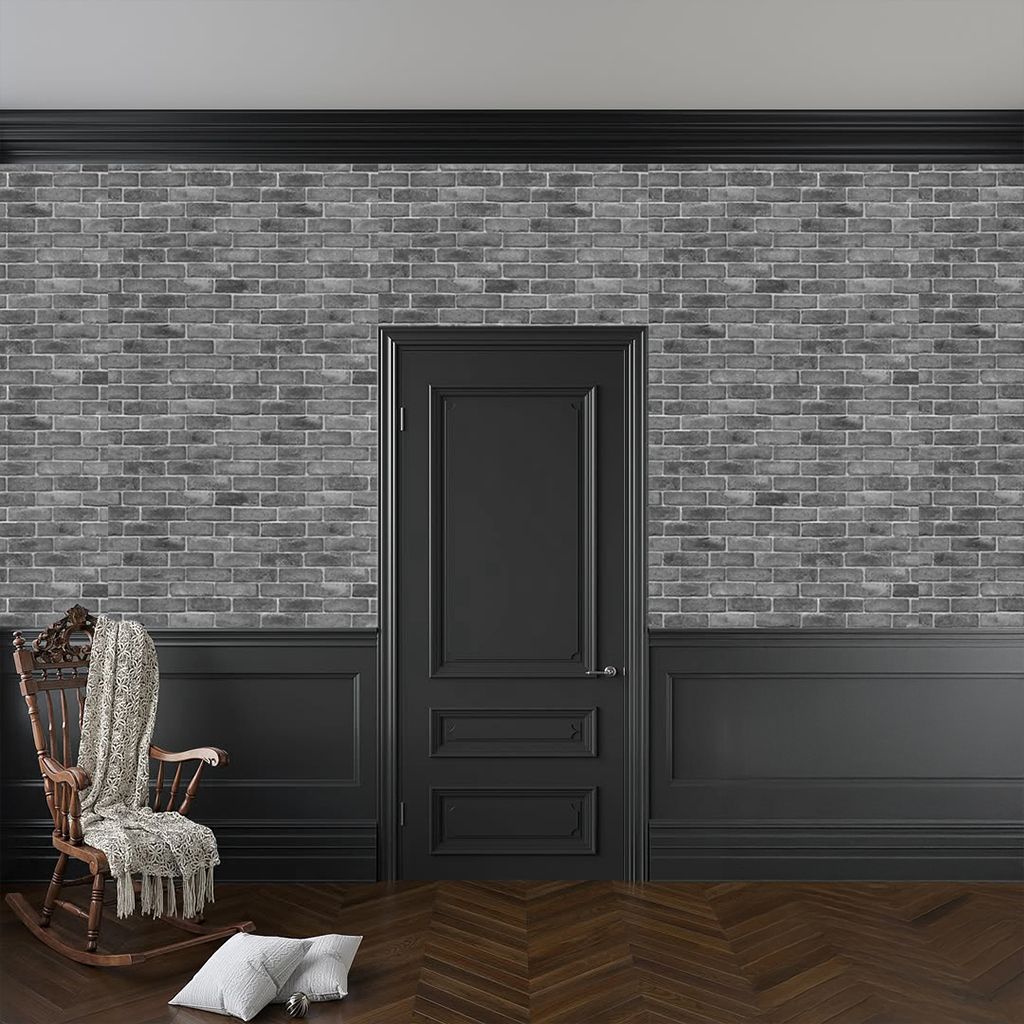 Habitación vacía con paredes revestidas de paneles oscuros, puerta negra, silla de mimbre y dos cojines .