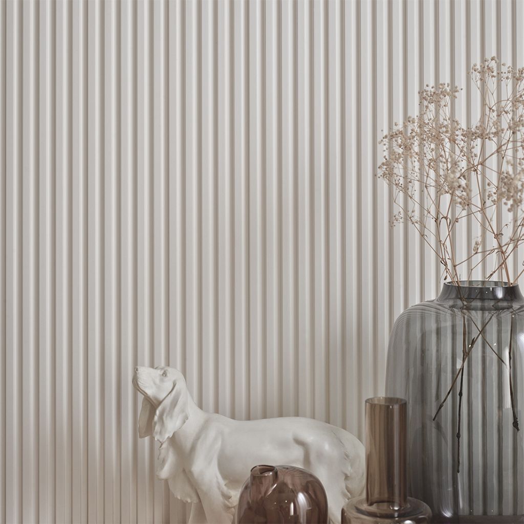 Sala de estar minimalista en tonos beige con sofá, otomana, lámpara de pie y mueble de madera con elementos decorativos.