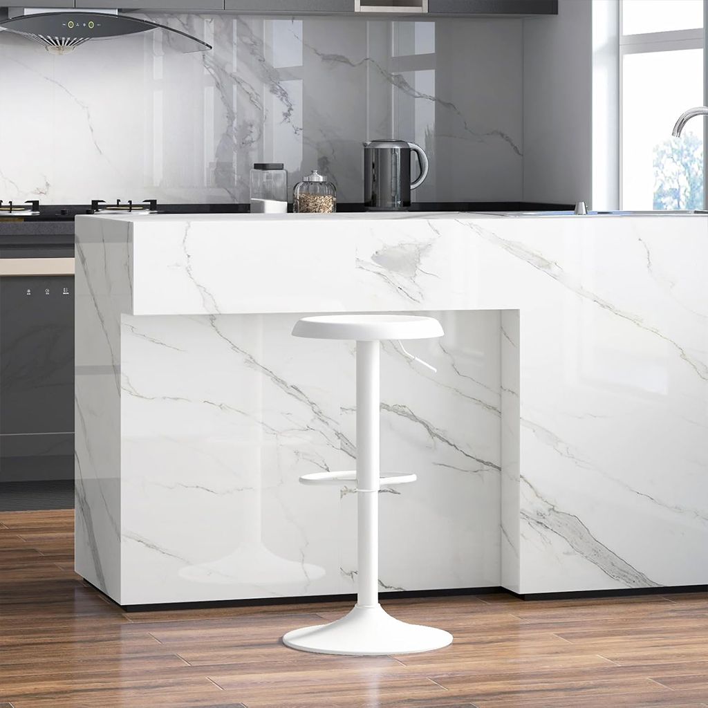 Moderna isla de cocina con tres taburetes de madera, paredes de mármol y plantas en macetas junto a una ventana luminosa.