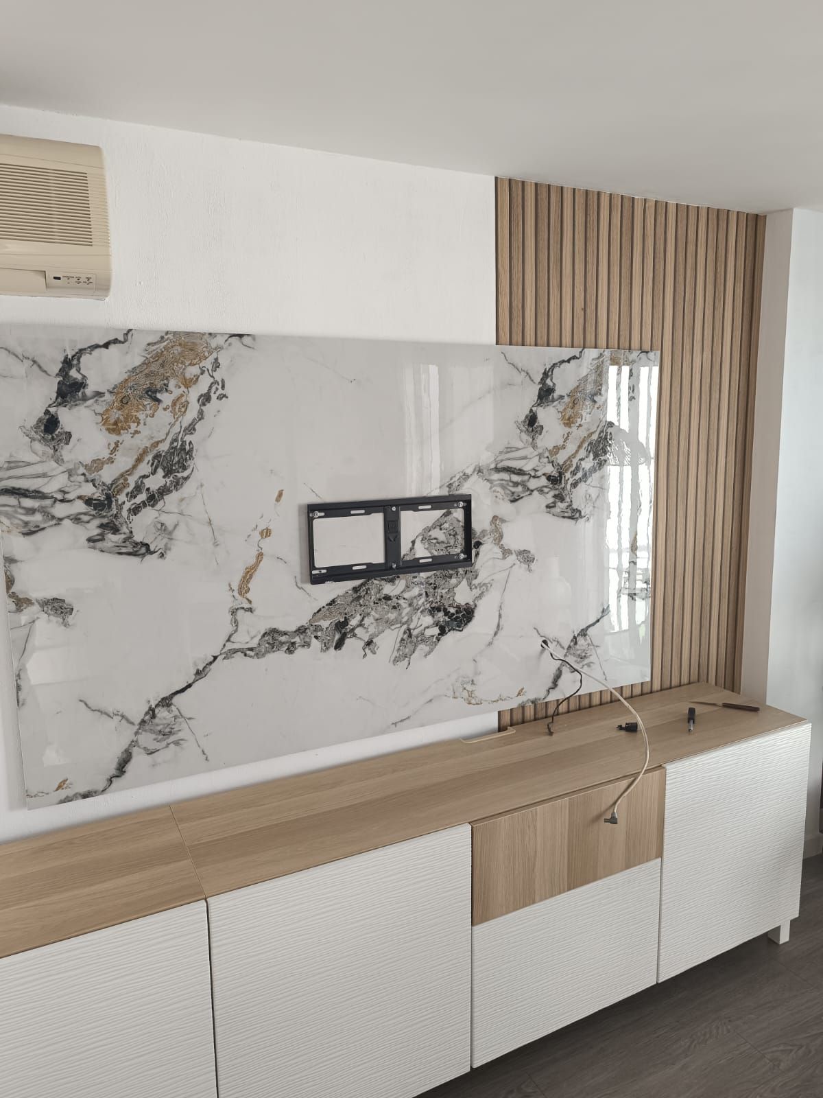 Entrada interior moderna con pared revestida de madera, panel decorativo de mármol, consola flotante negra